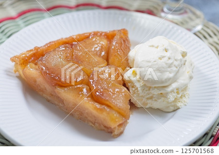 Slice of apple tarte tatin with scoop of whipped cream, french upside down cake, horizontal closeup 125701568