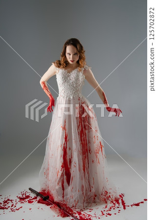 Bridal beauty embraces darkness with katana and bloodstains in haunting elegance 125702872