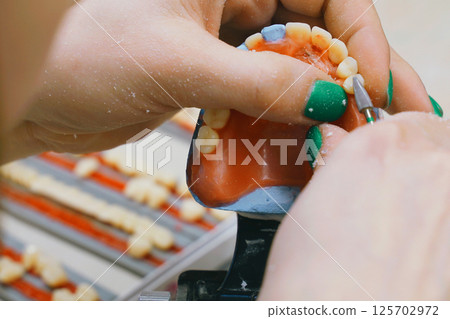 Expert dental technician skillfully shaping dentures in laboratory setting 125702972