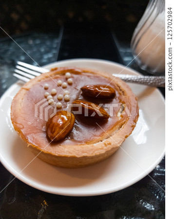 Sweet delicacy adorned with almonds served on a white plate 125702984
