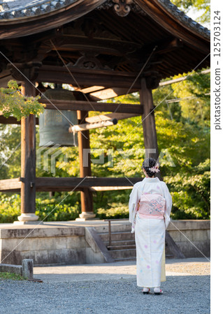 京都一座寺廟裡,一位身著和服的女子站在寺廟的鐘旁 京都一座寺廟裡,一位身著和服的女子站在寺廟的鐘旁 125703124