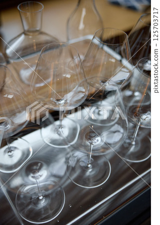 Clean wine glasses are on the table of a special wine cabinet, stylish table setting, ice, bottle of sparkling wine, light from window, decanter and degasser Clean wine glasses are on the table of a special wine cabinet, stylish table setting, ice, bottle of sparkling wine, light from window, decanter and degasser 125703717
