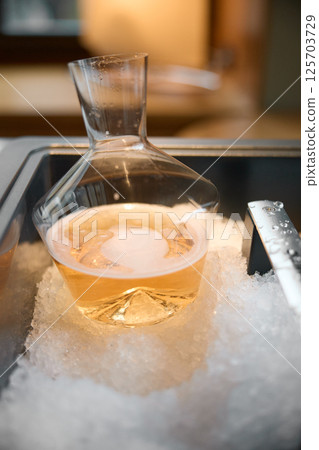 Decanter of rose champagne is cooled in a niche with ice in the restaurant, local lighting, wine cabinet, bubbles Decanter of rose champagne is cooled in a niche with ice in the restaurant, local lighting, wine cabinet, bubbles 125703729