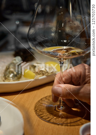 Champagne tasting, Wine glasses are on the table, stylish table setting, wine is poured from a bottle and decanter, sparkling wine bubbles, snacks, people smell the aroma and taste the wine Champagne tasting, Wine glasses are on the table, stylish table setting, wine is poured from a bottle and decanter, sparkling wine bubbles, snacks, people smell the aroma and taste the wine 125703730