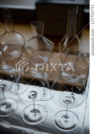 Clean wine glasses are on the table of a special wine cabinet, stylish table setting, ice, bottle of sparkling wine, light from window, decanter and degasser 125703731