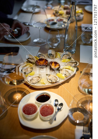 Champagne tasting, Wine glasses are on the table, stylish table setting, sparkling wine bubbles, oysters and sea urchins, special sauce Champagne tasting, Wine glasses are on the table, stylish table setting, sparkling wine bubbles, oysters and sea urchins, special sauce 125703797