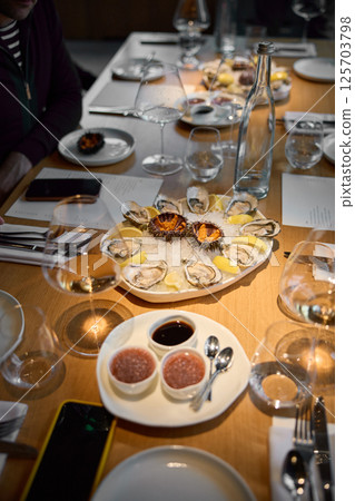 Champagne tasting, Wine glasses are on the table, stylish table setting, sparkling wine bubbles, oysters and sea urchins, special sauce 125703798