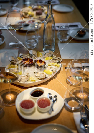 Champagne tasting, Wine glasses are on the table, stylish table setting, sparkling wine bubbles, oysters and sea urchins, special sauce Champagne tasting, Wine glasses are on the table, stylish table setting, sparkling wine bubbles, oysters and sea urchins, special sauce 125703799