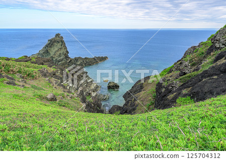 石垣島深淵岩,大神崎的綠色海岬和多雲天空下的藍色大海 石垣島深淵岩,大神崎的綠色海岬和多雲天空下的藍色大海 125704312