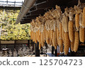 Corn hanging from the eaves of an old house 125704723