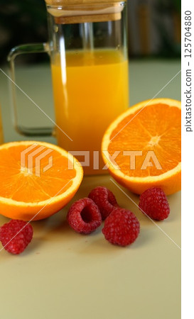 Glass jars filled with citrus and berry juices showcase tropical vegan refreshment, inspired by vibrant produce. Emphasizing sustainable health, eco-conscious living, and wellness. 125704880