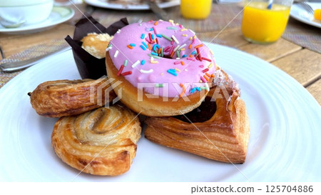 Sweet breakfast delight includes frosted donut and puff pastries with rich layers, playful pastel colors enhance sugary scene full of morning joy and colorful dessert satisfaction breakfast Sweet breakfast delight includes frosted donut and puff pastries with rich layers, playful pastel colors enhance sugary scene full of morning joy and colorful dessert satisfaction breakfast 125704886