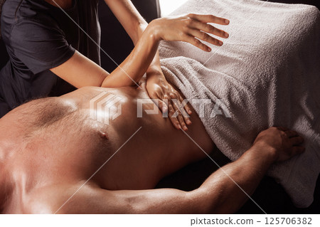 Massage therapist performing deep abdominal and diaphragm massage for muscle release and energy flow. Massage therapist performing deep abdominal and diaphragm massage for muscle release and energy flow. 125706382