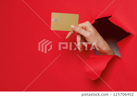 Close up of woman holding mockup of golden bank credit card with online service on red background. Close up of woman holding mockup of golden bank credit card with online service on red background. 125706402