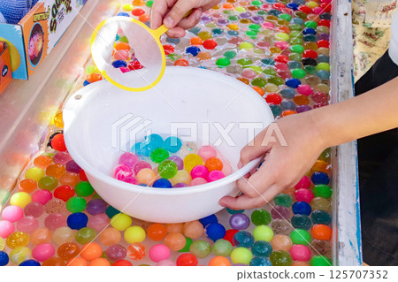 Child's hands scooping up super balls (7-year-old boy) 125707352