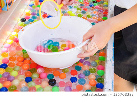 Child's hands scooping up super balls (7-year-old boy) 125708382