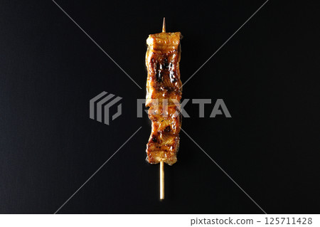 在黑色背景下拍攝的烤鰻魚串 在黑色背景下拍攝的烤鰻魚串 125711428