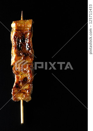 在黑色背景下拍攝的烤鰻魚串 在黑色背景下拍攝的烤鰻魚串 125711433
