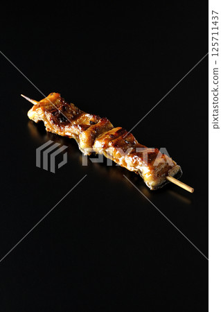 在黑色背景下拍攝的烤鰻魚串 在黑色背景下拍攝的烤鰻魚串 125711437