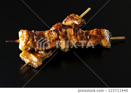 在黑色背景下拍攝的烤鰻魚串 在黑色背景下拍攝的烤鰻魚串 125711440