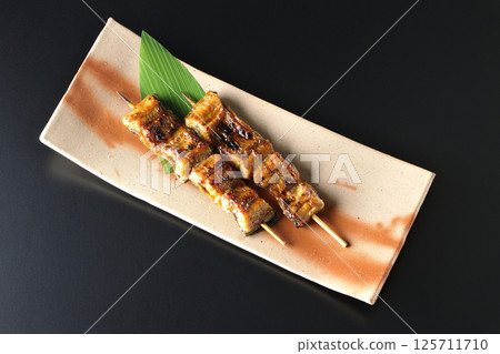 在黑色背景下拍攝的烤鰻魚串 125711710