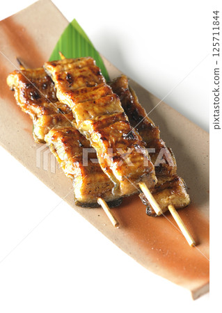 白色背景下拍攝的烤鰻魚串 白色背景下拍攝的烤鰻魚串 125711844