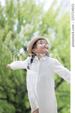 Full body of a running girl playing in the park, looking up and smiling 125714052