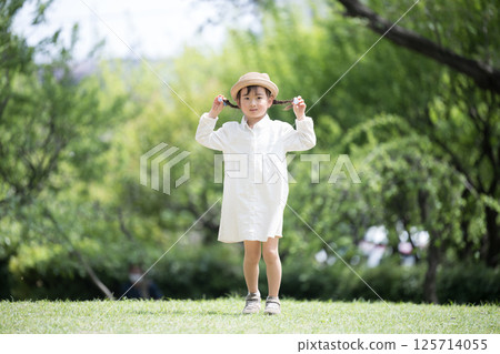 Full body front view of a girl with braids and cute hat playing in the park Full body front view of a girl with braids and cute hat playing in the park 125714055