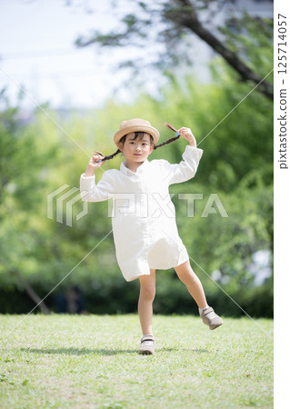 Full body front view of a girl with braids and cute hat playing in the park Full body front view of a girl with braids and cute hat playing in the park 125714057