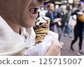 Cropped Man Biting Cannoli Dessert, Traditional Sicilian Pastry, Tube-shaped Shell Of Fried Pastry Dough, Filled With A Sweet, Creamy Filling Containing Ricotta Cheese. Street Food. Horizontal 125715007
