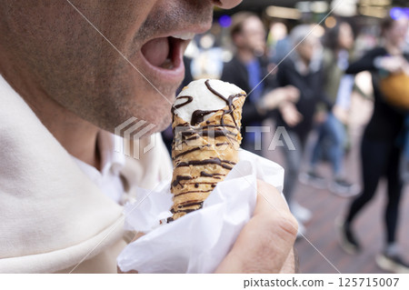 Cropped Man Biting Cannoli Dessert, Traditional Sicilian Pastry, Tube-shaped Shell Of Fried Pastry Dough, Filled With A Sweet, Creamy Filling Containing Ricotta Cheese. Street Food. Horizontal 125715007