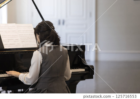 Back view of a junior high school girl playing piano Back view of a junior high school girl playing piano 125716553