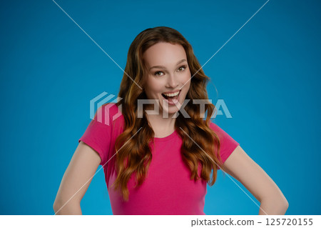 Woman posing with joy in studio against a blue background showcasing vibrant emotion and personality during a creative photoshoot 125720155