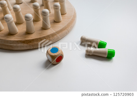 Wooden board game with colorful dice and pegs on white surface Wooden board game with colorful dice and pegs on white surface 125720903