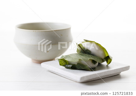 Kashiwa mochi and Cup of fresh matcha tea. Japanese sweet from mochi or rice cake and sweet red bean paste filling surrounded with Kashiwa or Oak leaf . Kashiwa mochi and Cup of fresh matcha tea. Japanese sweet from mochi or rice cake and sweet red bean paste filling surrounded with Kashiwa or Oak leaf . 125721833