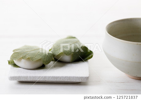 Kashiwa mochi and Cup of fresh matcha tea. Japanese sweet from mochi or rice cake and sweet red bean paste filling surrounded with Kashiwa or Oak leaf . Kashiwa mochi and Cup of fresh matcha tea. Japanese sweet from mochi or rice cake and sweet red bean paste filling surrounded with Kashiwa or Oak leaf . 125721837