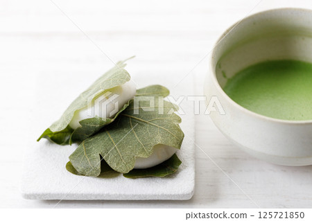 Kashiwa mochi and Cup of fresh matcha tea. Japanese sweet from mochi or rice cake and sweet red bean paste filling surrounded with Kashiwa or Oak leaf . 125721850