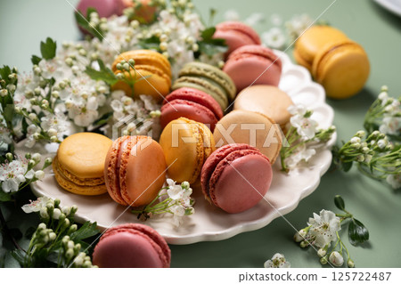 Colorful yellow, pink Macrons with spring flowers. Sweet dessert, sugar Colorful yellow, pink Macrons with spring flowers. Sweet dessert, sugar 125722487