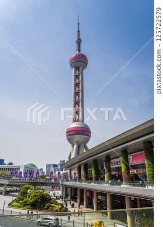 Shanghai, China - 1 April 2025: The Oriental Pearl Tower stands tall among skyscrapers, reflecting sunlight with its unique spherical design 125722579