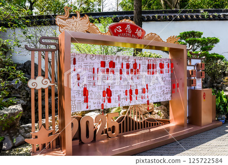 Shanghai, China - 2 April 2025: Traditional Chinese "Wishing Wall" installation with red and gold frames, hanging wish tags, and lucky fortune symbols in outdoor garden setting Shanghai, China - 2 April 2025: Traditional Chinese "Wishing Wall" installation with red and gold frames, hanging wish tags, and lucky fortune symbols in outdoor garden setting 125722584