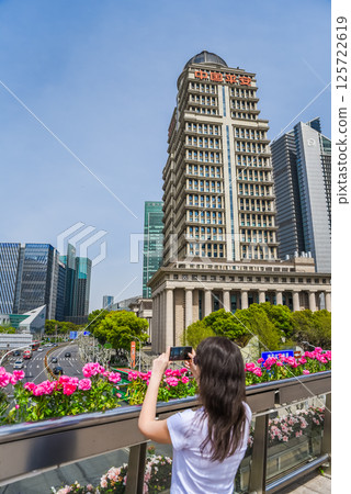 Shanghai, China - 1 April 2025: tourist photographs the Ping An Group building with red Ping An Insurance signage in Pudong on a sunny day 125722619