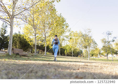 Young sportswoman running in a park during a sunny autumn day 125722940