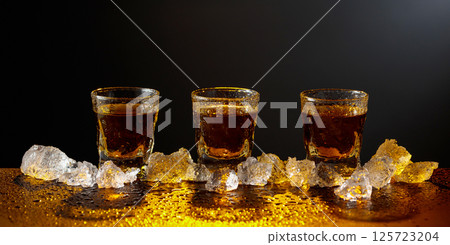 Whiskey and ice on a black table. Whiskey and ice on a black table. 125723204