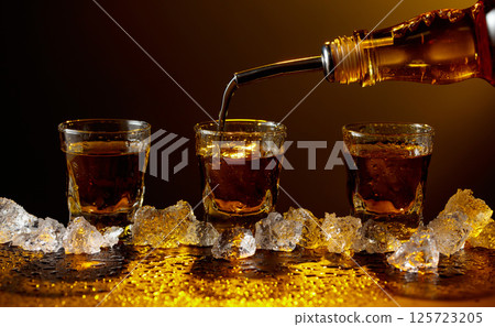 Whiskey pours from bottle to glass. 125723205