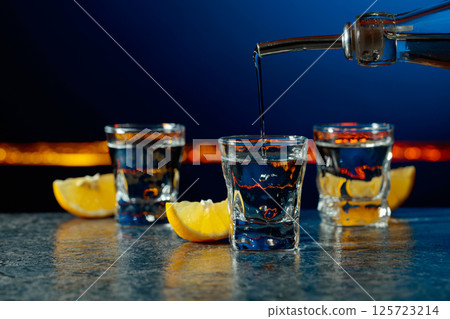 Vodka and lemon slices on a dark blue background. 125723214