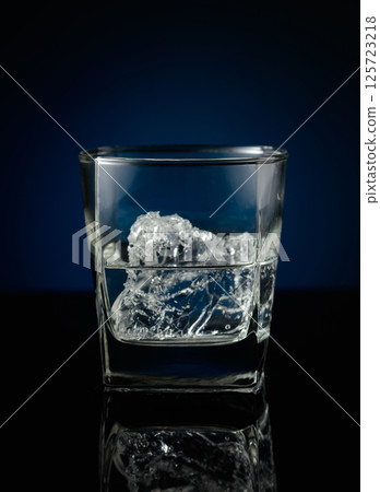 Vodka with ice on a black reflective background. 125723218