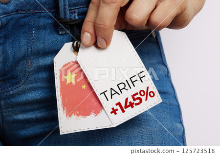 Hand Holding Jeans Price Tag with Tariff Marking 125723518
