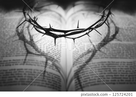 A crown of thorns symbolizing the sacrifice and suffering of Jesus Christ on the cross and a heart shadow reflected on a Bible, Holy Week background A crown of thorns symbolizing the sacrifice and suffering of Jesus Christ on the cross and a heart shadow reflected on a Bible, Holy Week background 125724201