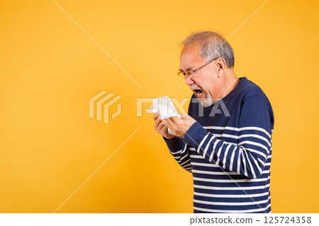 Portrait senior old man blowing nose with tissue studio shot isolated on yellow background, Asian elder man cold having flu and sneezing from sickness virus problem use tissue, pensioner unwell Portrait senior old man blowing nose with tissue studio shot isolated on yellow background, Asian elder man cold having flu and sneezing from sickness virus problem use tissue, pensioner unwell 125724358
