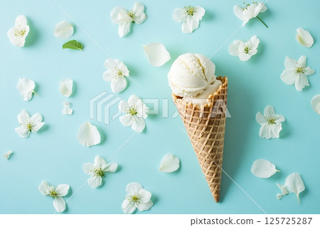 Waffle cone with ice cream and flowers petals on blue background Waffle cone with ice cream and flowers petals on blue background 125725287